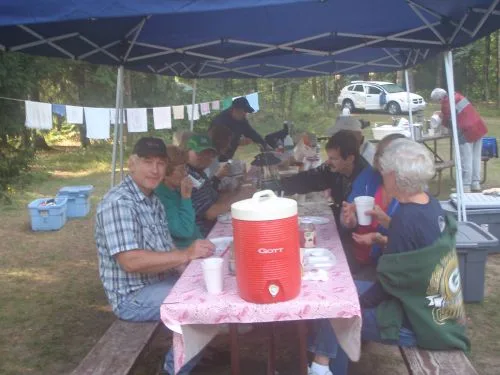 CWN campers sharing a meal at a picnic table under a canopy