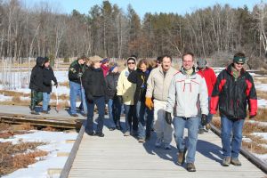 About fifteen CWN members walking a snowy boardwalk at Schmeeckle Reserve