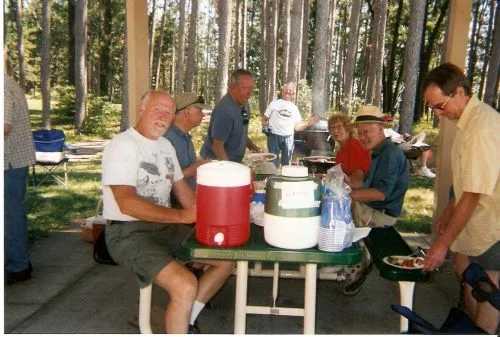 CWN members around a picnic table with coolers under a shelter at Lake Wazeecha