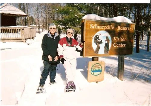Two CWN members on snowshoes beside the Schmeeckle Reserve Visitor Center sign