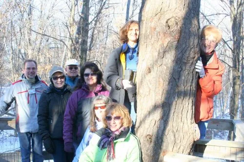 CWN members gathered around a large tree on a winter hike